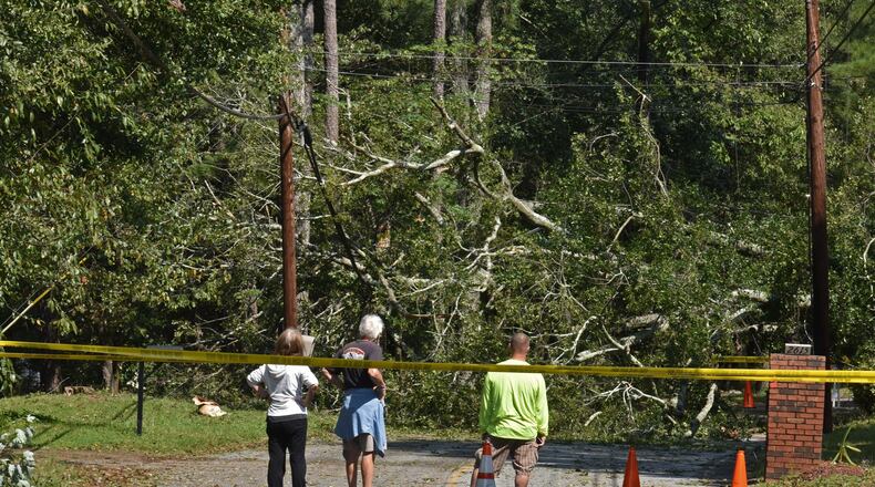 Residents watch over a huge fallen tree that caused the loss of the power in the neighborhood on Old Norcross Road in Tucker following Tropical Storm Irma, which swept across the metro area last week. Between 400 and 500 tons of debris related to the storm was brought to the DeKalb County landfill last week in just the initial stages of the cleanup. HYOSUB SHIN / HSHIN@AJC.COM