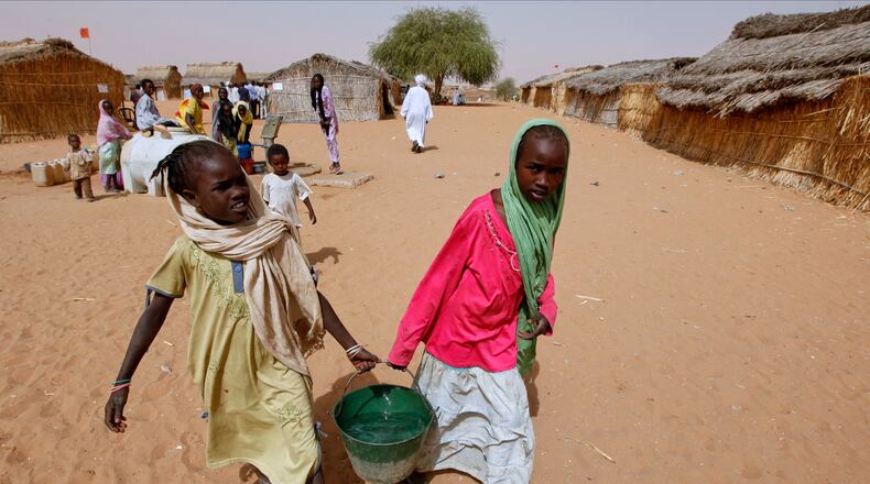 FILE - Sudanese refugee girls carry water supplies near a polling station in the refugee camp of Zamzam, on the outskirts of El Fasher, Darfur, Sudan, on April 13, 2010. (AP Photo/Nasser Nasser, File)