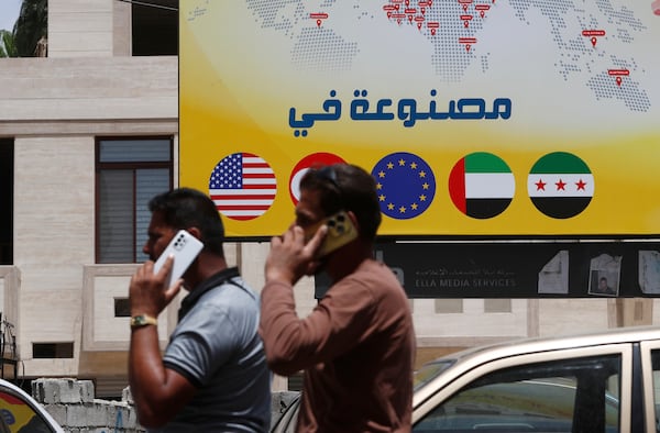 Syrian men speak on their phones on a street in Damascus, Syria, Wednesday, May 14, 2025. (AP Photo/Omar Sanadiki)