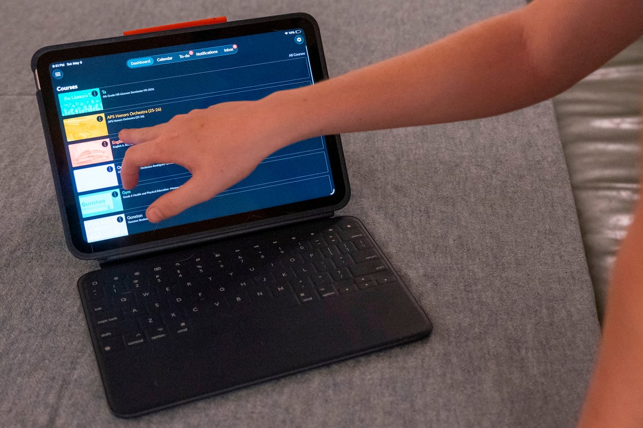 LuAnn Oliver's son demonstrates how he uses an iPad for his classes during a meeting where a group of school parents discussed ways to push back against screen time at the children's school, Saturday, May 9, 2026 in Arlington, Va. (AP Photo/Kevin Wolf)