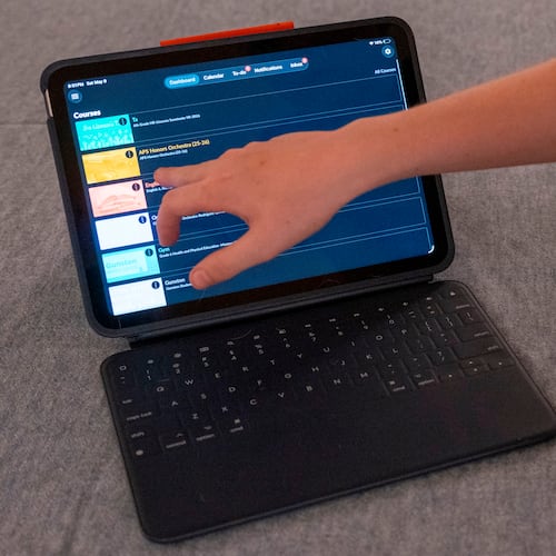 LuAnn Oliver's son demonstrates how he uses an iPad for his classes during a meeting where a group of school parents discussed ways to push back against screen time at the children's school, Saturday, May 9, 2026 in Arlington, Va. (AP Photo/Kevin Wolf)