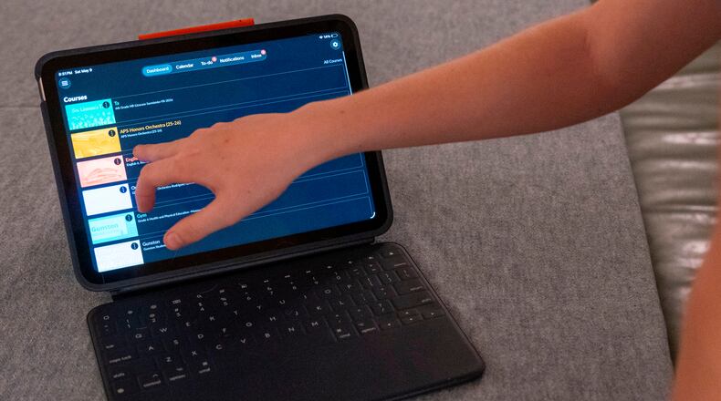 LuAnn Oliver's son demonstrates how he uses an iPad for his classes during a meeting where a group of school parents discussed ways to push back against screen time at the children's school, Saturday, May 9, 2026 in Arlington, Va. (AP Photo/Kevin Wolf)