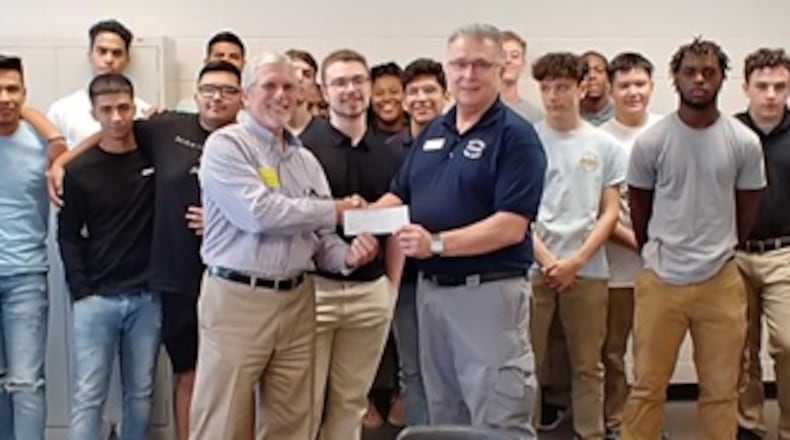 Tom Gardner, the owner of GHD Corporation in Norcross presents a check for $1,000 to Maxwell High Fire Services instructor Gary LaPrad as students look on. COURTESY OF GWINNETT COUNTY PUBLIC SCHOOLS