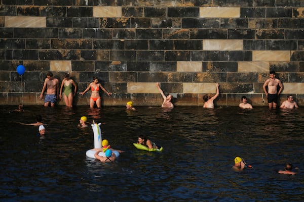 People swim in the river Spree to demand the lift of the hundred years old swimming ban at the river in Berlin, Germany, Tuesday, June 17, 2025. (AP Photo/Markus Schreiber)