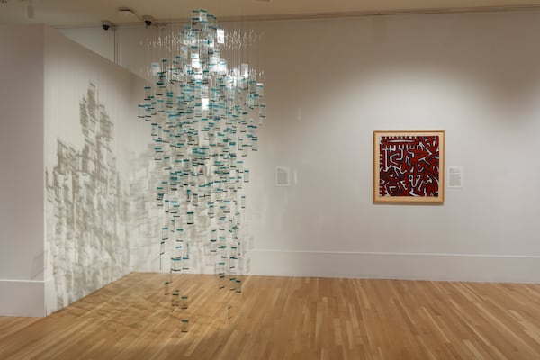 In Immy Mali’s "Virtually Mine," glass plates dangle from the ceiling, forming the ghostly outline of a man. Each plate carries fragments of text exchanges between Mali and her fiancé during a time when he worked abroad. (Courtesy of Michael C. Carlos Museum/Mike Jensen)