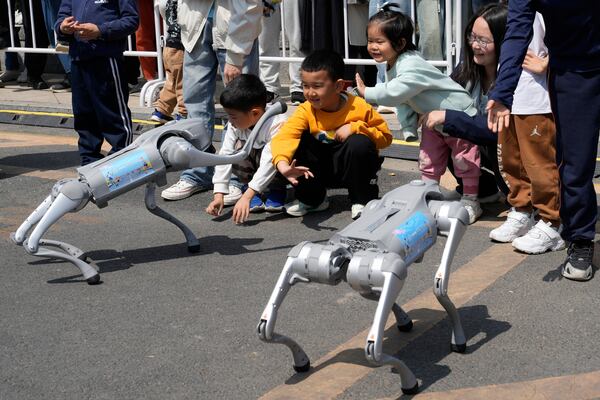 Children react to four legged robots performing before the award ceremony of the Humanoid Robot Half-Marathon held in Beijing on Saturday, April 19, 2025. (AP Photo/Ng Han Guan)