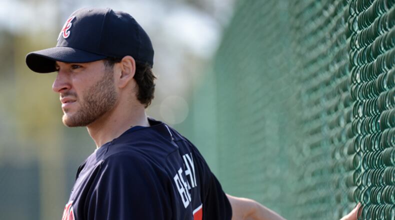 Braves starting pitcher Brandon Beachy stretches using a fence.