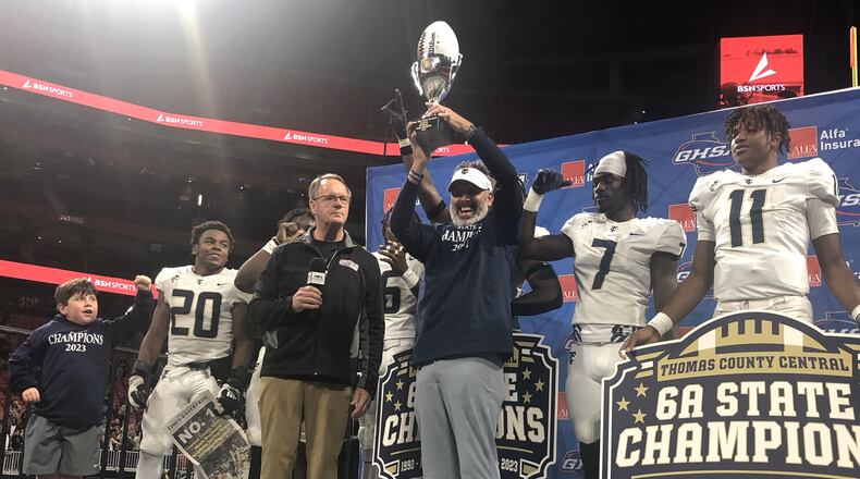 Thomas County Central head coach Justin Rogers accepts the championship trophy from GHSA executive Robin Hines after his teams 49-28 victory over Woodward Academy in the Class 6A final at Mercedes-Benz Stadium on Dec. 12, 2023.