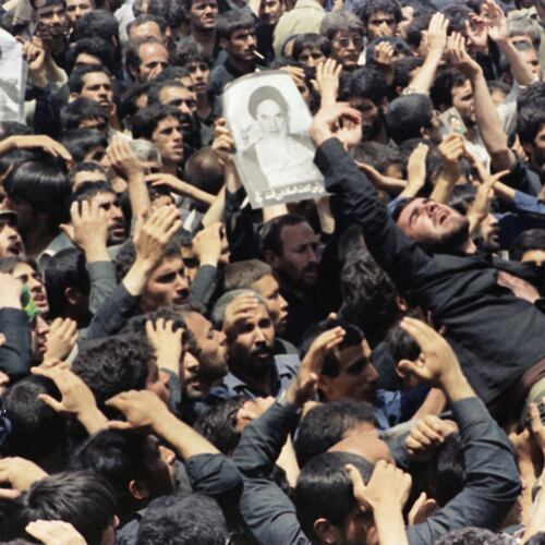FILE - An Iranian mourner goes into a frenzy just after the body of the Ayatollah Khomeini was removed from Beheshte Zahra Cemetery in Tehran, June 6, 1989. The burial was delayed when thousands of mourners crowded the imam's body in an effort to touch their leader. (AP Photo/Greg English, File)