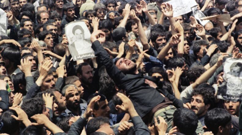 FILE - An Iranian mourner goes into a frenzy just after the body of the Ayatollah Khomeini was removed from Beheshte Zahra Cemetery in Tehran, June 6, 1989. The burial was delayed when thousands of mourners crowded the imam's body in an effort to touch their leader. (AP Photo/Greg English, File)