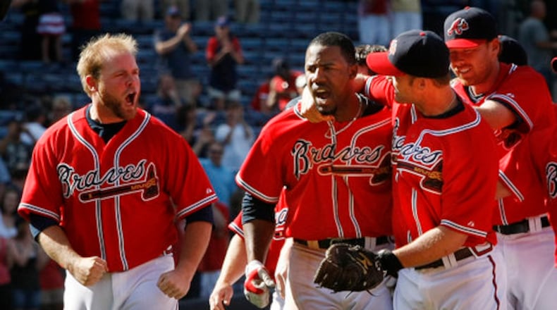 Braves catcher Brian McCann, left, cheers on (22) Jason Heyward, center as he is mobbed by David Ross and the rest of the Braves team after hitting a game winning single to score Martin Prado in the 9th for a 4-3 victory over the Rockies at Turner Field in Atlanta.