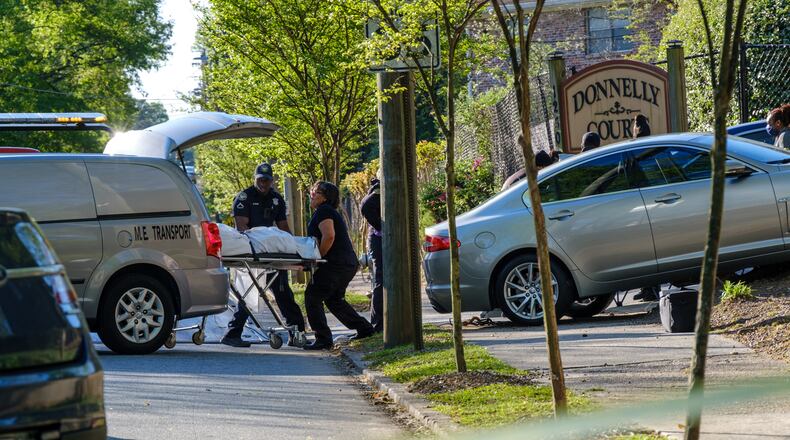 The body of a man who was found shot and dead inside a sedan is lifted into a van. The sedan crashed into a fence at a southwest Atlanta apartment complex on Friday, April 15, 2022. The crash occurred outside of the Donnelly Courts apartments. (Arvin Temkar / arvin.temkar@ajc.com)