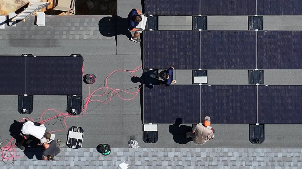 Workers with Custom Solar Solutions install solar panels on the roof of the Adler family home, Thursday, July 17, 2025, in North Druid Hills. (Hyosub Shin/AJC)