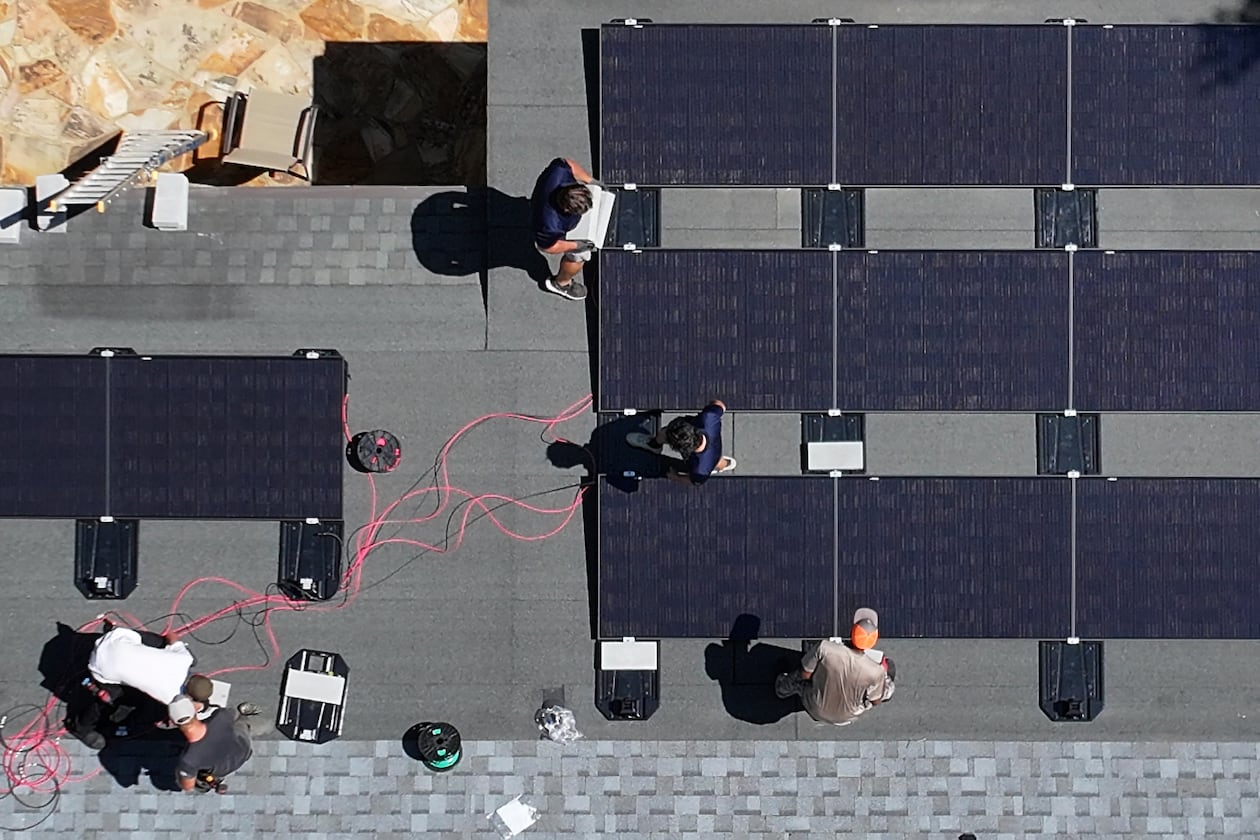 Workers with Custom Solar Solutions install solar panels on the roof of the Adler family home, Thursday, July 17, 2025, in North Druid Hills. (Hyosub Shin/AJC)