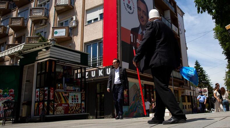 People pass by a giant election poster of acting prime minister Albin Kurti, in capital Pristina, Kosovo, Friday, June 5, 2026, ahead of snap parliamentary elections on June 7. (AP Photo/Visar Kryeziu)
