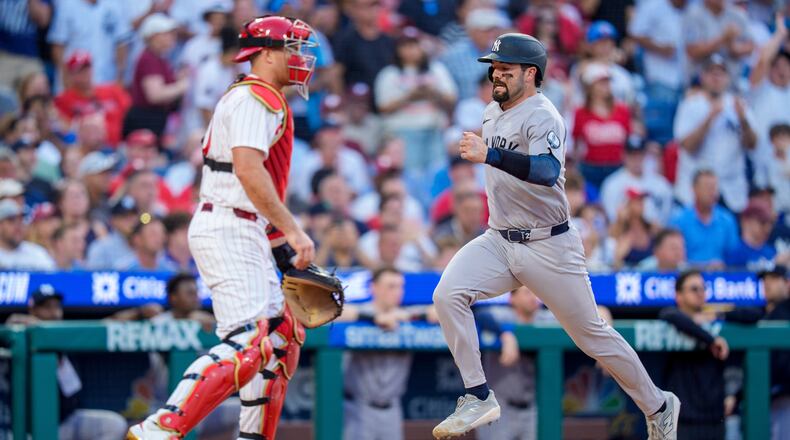 New York Yankees' Austin Wells, right, comes in to score on the single by Cody Bellinger as Philadelphia Phillies catcher J.T. Realmuto, left, looks on during the sixth inning of a baseball game, Saturday, July 25, 2026, in Philadelphia. (AP Photo/Chris Szagola)