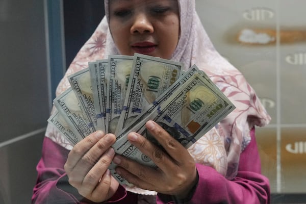 An employee shows US dollar bills at a money changer in Jakarta, Indonesia, Wednesday, July 16, 2025. (AP Photo/Tatan Syuflana)