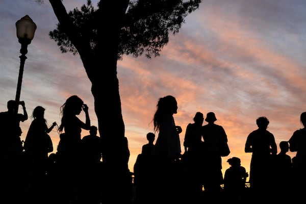 People watch the sun set from the Our Lady of the Hill viewpoint overlooking Lisbon at the end of a hot day in Lisbon, Friday, June 27, 2025. (AP Photo/Armando Franca)