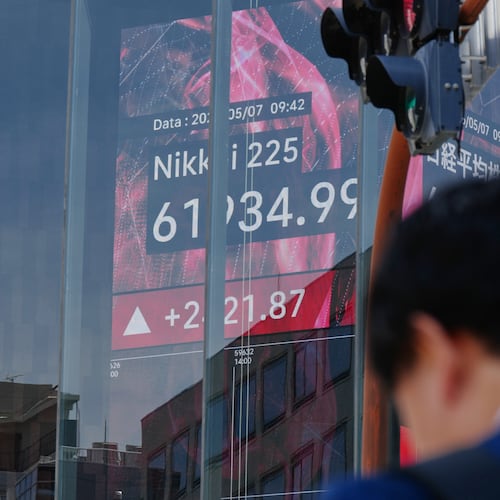 FILE - A person stands in front of an electronic stock board showing Japan's Nikkei index, seen through the glass wall of an office building in Tokyo, May 7, 2026. (AP Photo/Eugene Hoshiko, File)