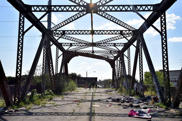 The so-called Bridge to Nowhere is located just north of Atlanta’s shiny new, billion-dollar Mercedes-Benz stadium. Closed in the early 1990s and partially demolished, it now serves as a shelter for a handful of homeless men and women. With a panoramic view of the city, what’s left of the bridge is now strewn with orange cones, plastic beads, tiki torches, piled up wrappers, and piles of garbage, tin foil with black burn markings, and syringes. A mattress. Leather couch. Blue tent. (Hyosub Shin / Hyosub.Shin@ajc.com)