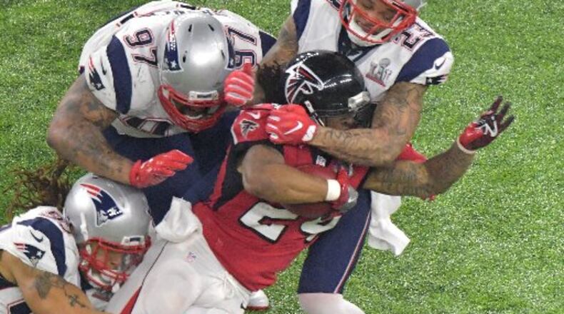 Atlanta Falcons running back Devonta Freeman (24) is brought down by New England Patriots defensive end Jabaal Sheard (93), defensive end Alan Branch (97) and strong safety Patrick Chung (23) in the second half at NRG Stadium in Houston on Sunday. The Patriots beat the Falcons in OT 34-28. HYOSUB SHIN / HSHIN@AJC.COM
