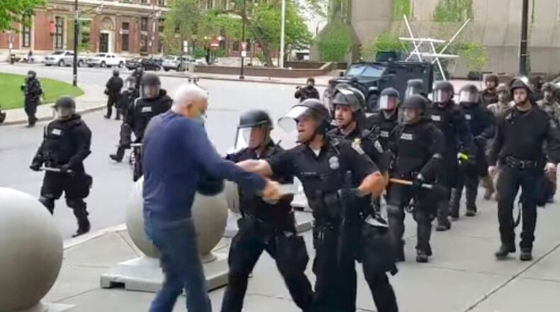 In this image from video provided by WBFO, a Buffalo police officer appears to shove a man who walked up to police Thursday, June 4, 2020, in Buffalo, N.Y. Video from WBFO shows the man appearing to hit his head on the pavement, with blood leaking out as officers walk past to clear Niagara Square. (Mike Desmond/WBFO via AP)