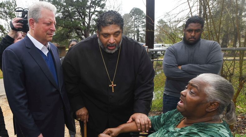 FILE - In this Feb. 21, 2019, file photo, former Vice President Al Gore, left, founder of the Climate Reality Project, and the Rev. William Barber II, president of the Repairers of the Breach, visit Lowndes County resident Charlie Mae Holcombe to talk about the failing wastewater sanitation system at her home in Hayneville, Ala. An anti-poverty coalition led by Barber is scheduled to hold a virtual march Saturday. The Mass Poor People’s Assembly & Moral March on Washington aims to build upon the nation’s principles to pursue solutions to poverty — something advocates say is getting especially severe in rural areas. (AP Photo/Julie Bennett, File)