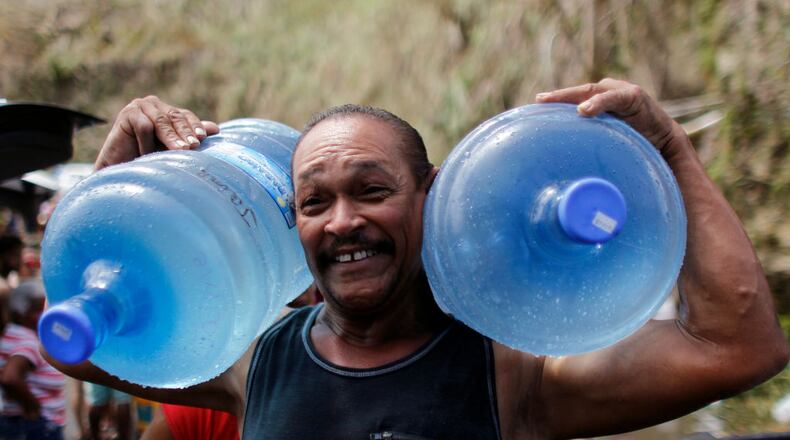 A man carries two water jugs filled with water near San Juan.