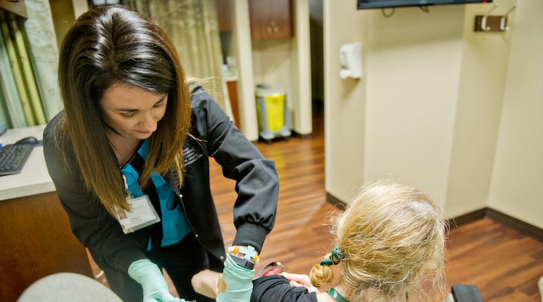 Brittany Deraney (left) holds a patient's arm as she injects her with medication at the Cancer Treatment Centers of America's Southeastern Regional Medical Center in Newnan.