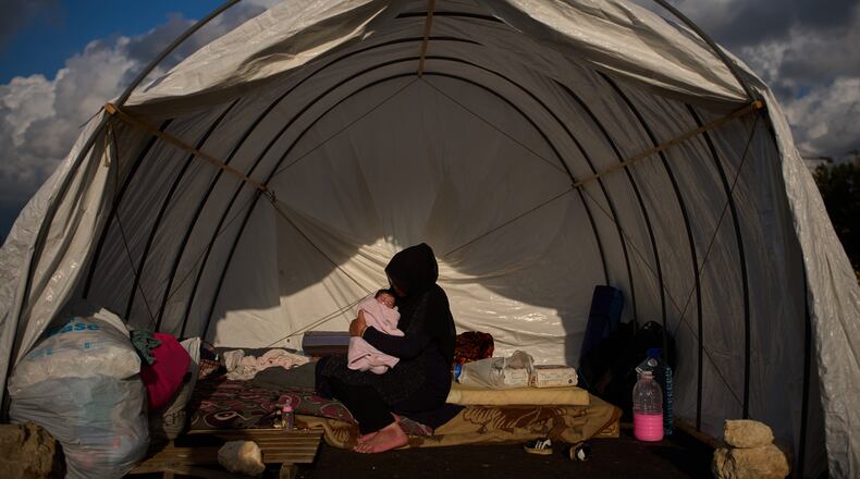 Haifa Kenjo, who fled Israeli airstrikes on the southern suburbs of Beirut, holds her 15-day-old daughter Shiman inside the tent she uses as a shelter and where she gave birth to her in Beirut, Sunday, April 12, 2026. (AP Photo/Emilio Morenatti)