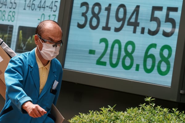 A person walks in front of an electronic stock board showing Japan's Nikkei index at a securities firm Monday, June 23, 2025, in Tokyo. (AP Photo/Eugene Hoshiko)