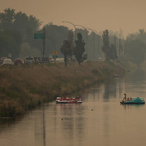 People float on the Channel Pathway that connects Okanagan Lake and Skaha Lake as smoke from wildfires burning in the region fills the air, in Penticton, British Columbia, Monday, Aug. 10, 2026. (Darryl Dyck/The Canadian Press via AP)