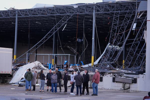 Warehouse workers gather at the site of a storm damaged warehouse in Brownsburg, Ind., Thursday, April 3, 2025. (AP Photo/Michael Conroy)