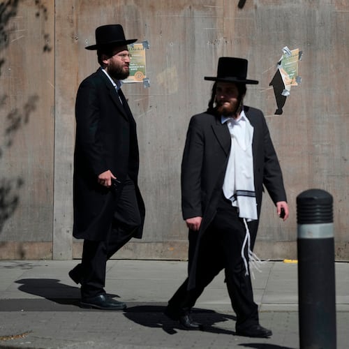 Two men walk in London, Thursday, April 30, 2026, near the scene where two people were recently stabbed in the Golders Green neighbourhood, that has a large Jewish community. (AP Photo/Alastair Grant)