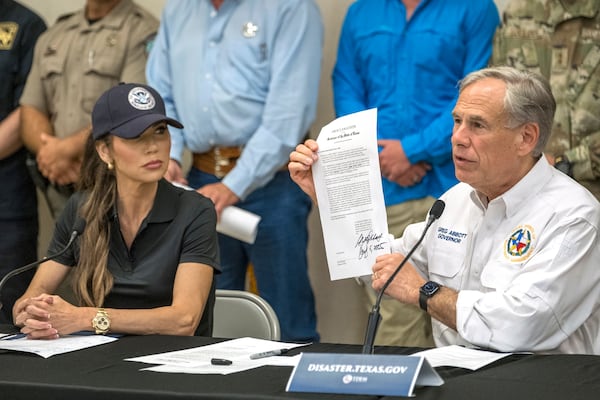Texas Gov. Greg Abbott signs and holds up an disaster declaration proclamation as Homeland Security Secretary Kristi Noem, left, looks on during a press conference about recent flooding along the Guadalupe River, Saturday, July 5, 2025, in Kerrville, Texas. (AP Photo/Rodolfo Gonzalez)