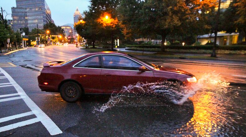 Flooded roads could have significant damage hidden by floodwaters. NEVER drive through floodwaters or on flooded roads. Water only one foot deep can float most automobiles. This photo was taken during a summer storm. Cars splash through the standing water along Peachtree Street in Midtown Atlanta near Beverly Road. (John Spink/AJC)