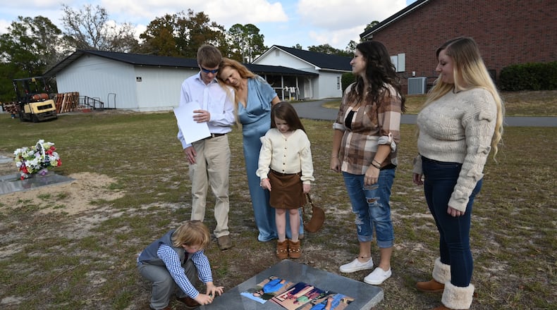 Angie McBrayer, ex-wife of James Aaron McBrayer, leans her head on her son Sam McBrayer as she and her three children and two grandchildren (from left) Jackson McBrayer, 3, Piper Jae McBrayer, 7, Katy Isaza, and Jordan McBrayer, visit the grave of James McBrayer, Thursday, November 20, 2025, in Tifton. He died after being restrained by Tift County sheriff's deputies on April 24, 2019. His ex-wife witnessed the arrest and said she thought the deputies were being rough but did not imagine that McBrayer would die. (Hyosub Shin/AJC)
