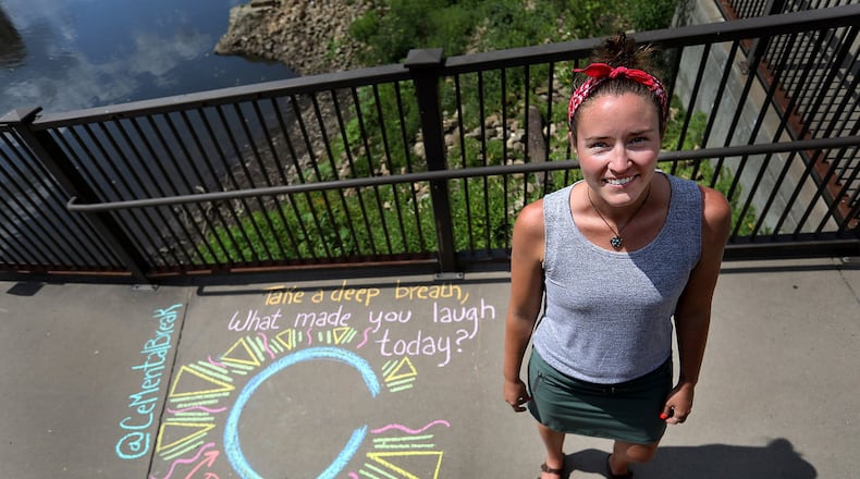 Taylor Tinkham stands next to a chalk drawing she made as part of CeMental Breaks, a movement she started and is hoping will catch on across the state, where she creates chalk drawings in public places encouraging mindfulness and reflection. Tinkham is seen near Water Power Park on Tuesday, Aug. 6, 2019, in Minneapolis, Minn. (David Joles/Minneapolis Star Tribune/TNS)