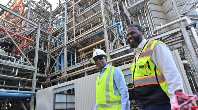 Chris Womack, chairman, president and CEO of Georgia Power (left), is accompanied by Kevin Lofton, an operations team leader, on a visit to a testing site where a group of engineers burn hydrogen using existing infrastructure at Georgia Power’s Plant McDonough-Atkinson, on Wednesday, June 8, 2022. (Hyosub Shin / Hyosub.Shin@ajc.com)