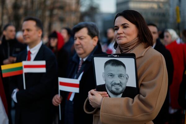 FILE - Belarusian opposition leader Sviatlana Tsikhanouskaya, right, holds a photo of her imprisoned husband, Syarhei Tsikhanouski as she attends a celebration marking the 107th anniversary of the declaration of independence of the Belarusian People's Republic, in Vilnius, Lithuania, on March 25, 2025. (AP Photo/Mindaugas Kulbis, File)