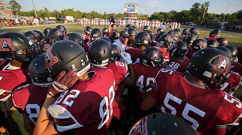 Alpharetta head coach Jacob Nichols, center, huddles with the team before a game. JASON GETZ / SPECIAL