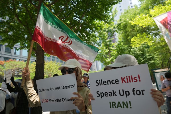 People hold an Iranian flag and signs during a rally demanding to stop the war between Israel and Iran, in Seoul, South Korea, Sunday, June 22, 2025. (AP Photo/Lee Jin-man)