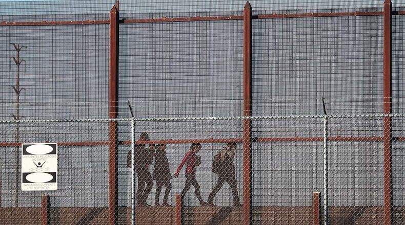 Migrants walk together along the U.S./Mexican border wall as they look to turn themselves over to the U.S. Border Patrol as they seek asylum in the United States on June 04, 2019 in El Paso, Texas. (Photo by Joe Raedle/Getty Images)