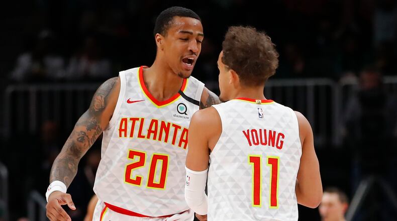 Hawks forward John Collins (20) reacts with guard Trae Young (11) in the first half of an NBA basketball game against the Boston Celtics on Monday, Feb. 3, 2020, in Atlanta. (AP Photo/Todd Kirkland)
