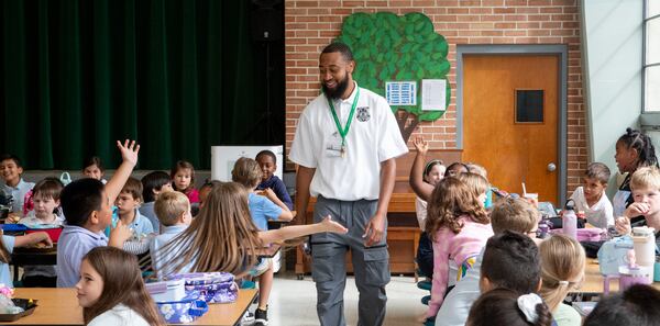 Vincent Rhynes, a DeKalb County School District security associate, walks through the Ashford Park Elementary cafeteria to students' delight in 2024. Today, the school enrolls nearly twice as many students as it has the capacity for, according to district records. (Jenni Girtman for the AJC)