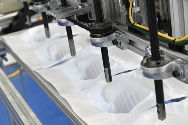 Tomas Nedbal (not pictured) demonstrates a cutting station that is part of an N95 mask production line being developed at ThermoPore Materials Corporation, a plastics manufacturer in Newnan. ThermoPore received government approval to make a new type of N95 that utilizes a different filtration material. (Hyosub Shin / Hyosub.Shin@ajc.com)