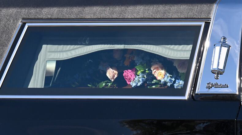 The casket of former first lady Rosalynn Carter is covered in flowers in the hearse outside the Rosalynn Carter Health & Human Services complex at Georgia Southwestern State University, Monday, November 27, 2023, in Americus. (Hyosub Shin / Hyosub.Shin@ajc.com)