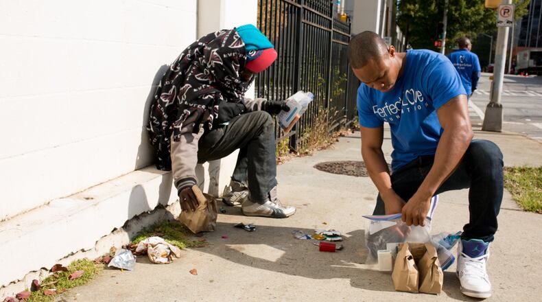 Taos Wynn, founder of the nonprofit Perfect Love Foundation, gives a sack lunch and a hygiene kit to a homeless man in downtown Atlanta. Distributing food is one of many acts of kindness the foundation does on a regular basis. CONTRIBUTED