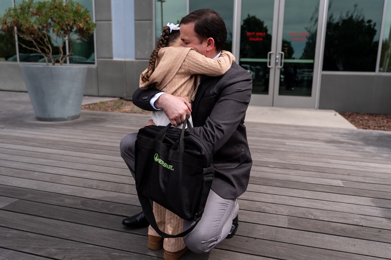 FILE - Milenko Faria, whose wife, Dr. Rubeliz Bolivar, is in immigration custody, hugs their daughter, Milena, after his asylum interview at the U.S. Citizenship and Immigration Services facility in Tustin, Calif., Thursday, April 16, 2026. (AP Photo/Jae C. Hong, File)