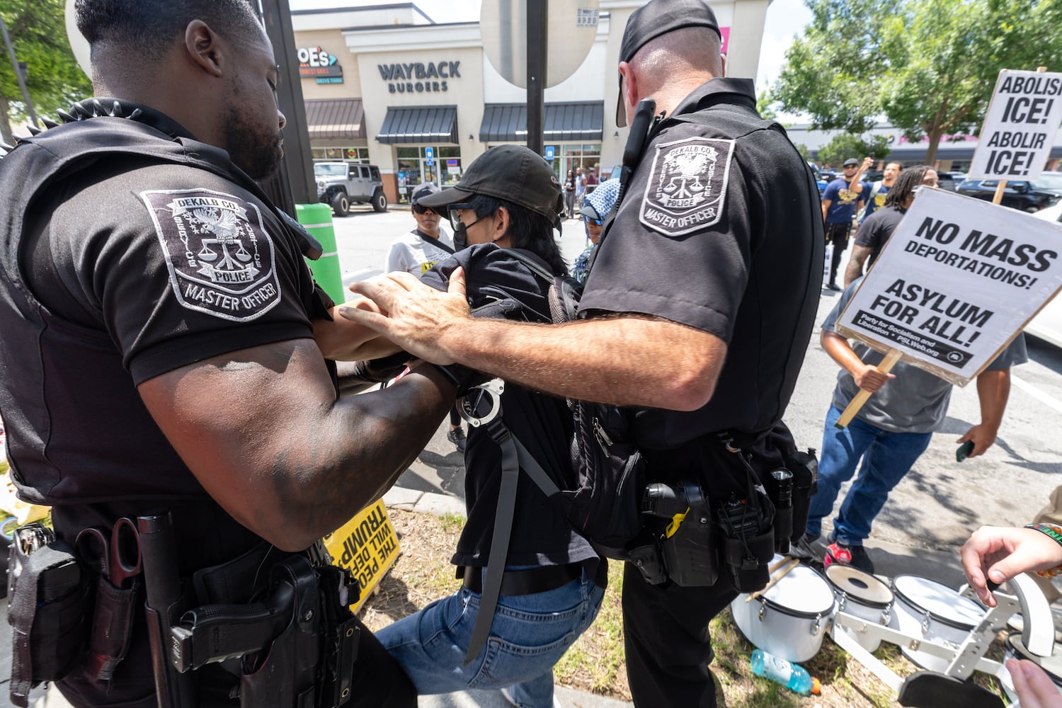 A demonstrator is arrested for refusing to take off their mask during a protest on ICE raids and deportation arrests on Chamblee-Tucker Road in Atlanta on Saturday, June 14, 2025. (Arvin Temkar / AJC)